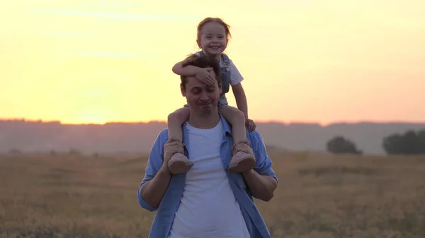 Dítě sedí na otcově krku a objímá svého milovaného otce. Roztomilé dítě si hraje s tátou. Šťastný rodinný otec s dítětem na ramenou. Bezstarostný rodič s dcerou v parku. šťastná rodina — Stock fotografie