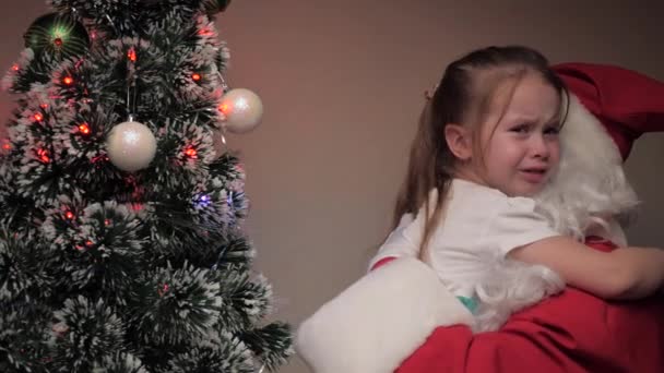 Niña llorando y abrazando a Santa Claus. El chico está molesto Santa Claus le calma. Felices fiestas infantiles. Cuento de hadas de invierno visitando al niño. Vacaciones de invierno año nuevo. Amable abuelo mágico — Vídeo de stock