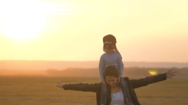 Mutlu aile, anne ve kızı parkta pilotçuluk oynuyor. Takım çalışması. Kızım ve annem bir uçakta uçmayı hayal ediyorlar. Süper kahraman bir çocuğun oğlu annesinin boynunda oturuyor. Bebeğinle hafta sonu oyna.