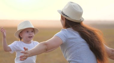 Mutlu küçük kız parkta annesini, çocuğunu ve annesini seviyor. Anne ve bebek kucaklaşması. Mutlu aile, çimenlerde oynayan anne ve kız. Mutlu aile ve sağlıklı çocuklar kavramı. Bebek annesini seviyor.