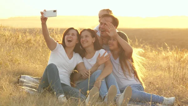 Szczęśliwej podróży rodzinnej. selfie na smartfonie w parku. Mama, tata i dzieci siedzą na kocu i kręcą film. Matka i ojciec z córkami są fotografowani na polu. rodzina blogerów — Zdjęcie stockowe