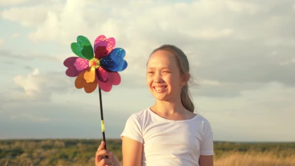 Girl playing pinwheel park in slow motion. Happy child playing having fun pinwheel. Happiness vacation childhood children happy family holiday. childhood concept. a child playing in park catches wind — Stock Video