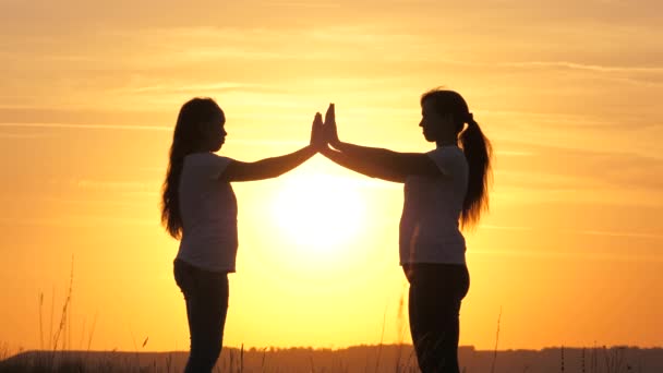 Mom and daughter touched their palms to each other, hands over a beautiful sunset. Happy family mom and daughter in field in sun. concept of a happy family of children and childhood. Mommy and kid — Stock Video