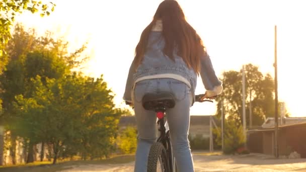 Girl Kid Riding Bike in Summer in City. Krásná dospívající dívka jezdí na kole v parku na ulici, slunečný den. Holka se kutálí, pohled zezadu. Puberťák jezdí na kole v parku. Zdravotní a sportovní koncept — Stock video