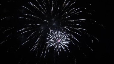 Siyah gökyüzünde renkli gece patlamaları. Gece gökyüzünde çok renkli güzel havai fişekler. Yeni yıl arifesi havai fişek kutlaması. Gece gökyüzünde havai fişek gibi parlayan ışıklar. Parlayan havai fişek gösterisi.