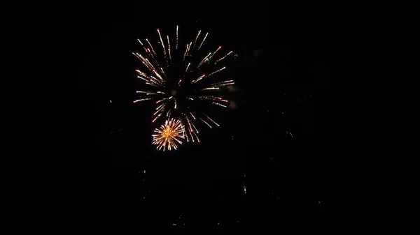 Πολύχρωμα πυροτεχνήματα στο νυχτερινό ουρανό. Λαμπερά πυροτεχνήματα με φώτα bokeh στο νυχτερινό ουρανό. Λαμπερό σόου πυροτεχνημάτων. Πρωτοχρονιάτικα πυροτεχνήματα. Όμορφες χρωματιστές εκρήξεις νύχτα στο μαύρο ουρανό — Φωτογραφία Αρχείου