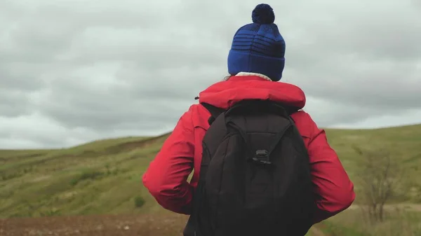 Un viaggiatore libero e felice con uno zaino va in montagna a braccia aperte, sorride e ride. Giovane donna sana viaggia nella natura godendo del bellissimo paesaggio delle colline. Concetto di viaggio. — Foto Stock