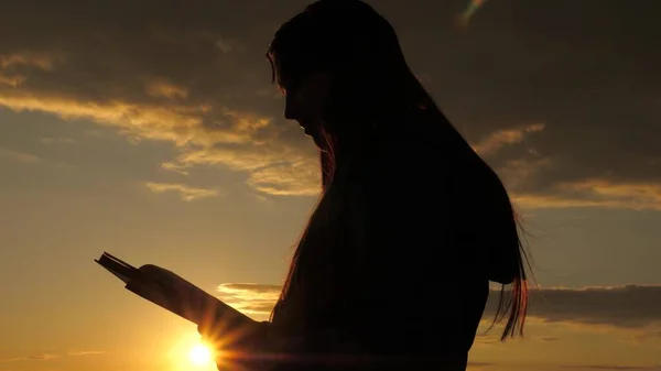 Una mujer lee un libro en rayos del sol. El hombre lee la Biblia al aire libre. Un hombre tiene la Biblia en sus manos y estudia la palabra de Dios al amanecer en la cima de la montaña. Buscando la verdad en las escrituras. —  Fotos de Stock