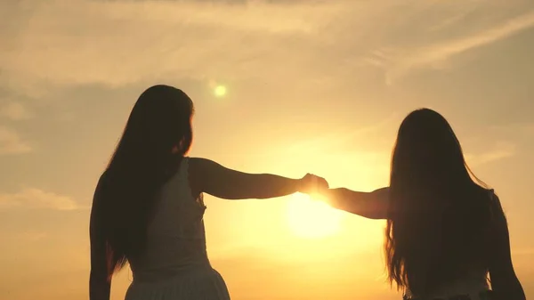 Bonne famille mère et fille dans un champ au coucher du soleil. Fille et mère étendent leurs mains au soleil. Concept de famille heureuse d'enfants. Maman et bébé marchent dans le parc — Photo