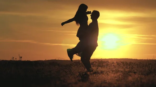 Gli amanti dell'uomo e della donna danzano nei raggi luminosi del sole nel campo. spensierata famiglia che balla al tramonto sulla spiaggia. Persone libere. Felice ragazzo che balla e gira con la sua ragazza in serata nel parco estivo. — Foto Stock