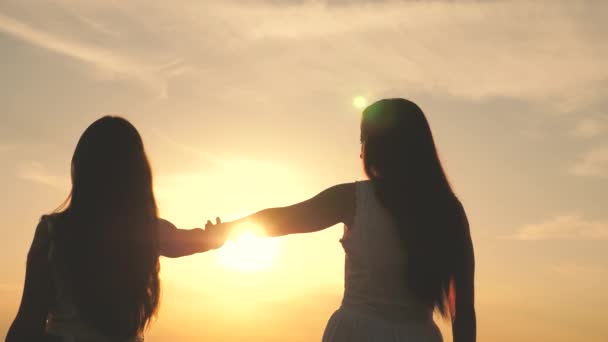 Young women stretch their hands to sun. Happy family mom and daughter in a field at sunset. Daughter and mother stretch their hands to sun. Concept of happy family of children. Family in the park — Stock Video