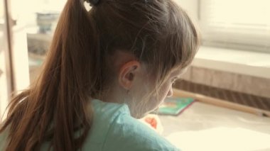 Çocuk ders yazıyor. Genç bir liseli kız not defterine notlar yazarak ev ödevi yapar. Uzaktan öğrenme konsepti. Öğrenci, liseli kız evde oturarak kendini eğitmekle meşgul..