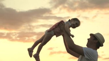 Şapkalı baba ve küçük sağlıklı çocuk birlikte oynuyorlar, gülüyorlar ve sarılıyorlar. Babam mavi gökyüzüne mutlu bir kız çocuğu fırlatıyor. İyi yolculuklar. Bebeğin ebeveynin kollarında. Baba izinli. Mutlu aile