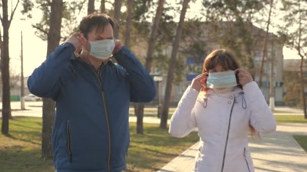 El hombre y la mujer se pusieron una máscara protectora en la calle, mostrando como. La gente se pone máscaras médicas para virus, pulgar hacia arriba. Concepto de salud y seguridad pandémica por Coronavirus, coronavirus, COVID-19. Protección contra virus — Vídeo de stock