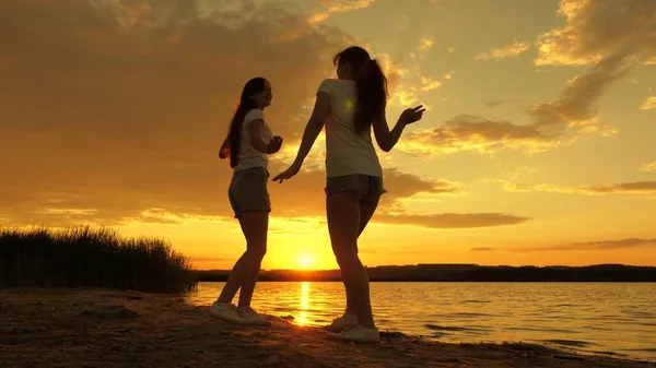 Celebrate a summer day with beach party. free girls are dancing cheerfully on summer evening at sunset. outdoor celebration. healthy teenagers cheerfully raise their hands up. a fun holiday on shore. — Stock Photo, Image