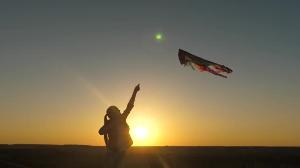 Szczęśliwa dziewczyna biegnie z latawcem w rękach przez pole w promieniach zachodu słońca. Zdrowe dziecko marzy o wolności, ucieczce. Dzieciak bawi się na zewnątrz w parku. Nastolatek chce być pilotem. — Wideo stockowe