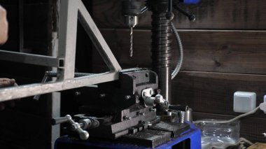 Bir tamirci atölyedeki bir parçayı ölçer. Bir sondaj makinesi metal bir kısımda delik açar. Çilingir dükkanındaki bir fabrikada çilingir. Sondaj makinesi. Sürücü demir işyerinde delik açıyor.