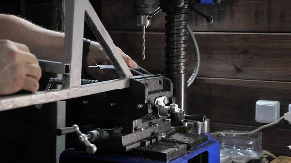Ένας μηχανικός μετράει ένα μέρος σε ένα εργαστήριο. Μια μηχανή γεώτρησης ανοίγει μια τρύπα σε ένα μεταλλικό μέρος. Ένας κλειδαράς σε ένα εργοστάσιο σε ένα κατάστημα κλειδαράδων. Τρυπάνι. Ο οδηγός τρυπάει το σιδερένιο αντικείμενο. — Φωτογραφία Αρχείου