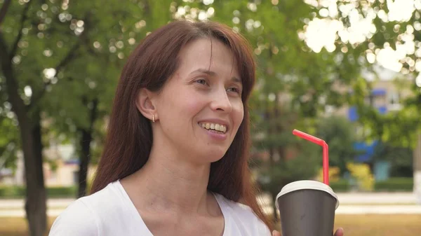 Jovem mulher de negócios bonita está andando no parque da cidade sorrindo com uma xícara de delicioso café takeaway. menina feliz beber chá aromático quente ao ar livre. — Fotografia de Stock