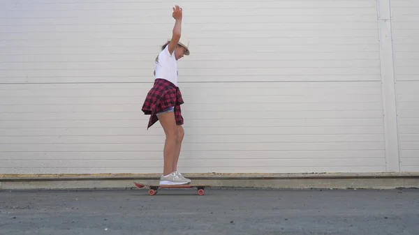 Meisjes leren buiten skateboarden. Gelukkige tiener skateboarder rijdt door straat in de stad. Modieuze tiener die op straat rust. Gezond en gelukkig levensstijl concept. — Stockfoto