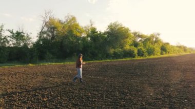 Bir çiftçi ekmeden önce toprağın kalitesini kontrol eder. İş kadını tarlayı kontrol ediyor. Tarlada tableti olan çiftçi kadın. Dişi bir tarım uzmanı tohum ekmenin kalitesini kontrol eder..