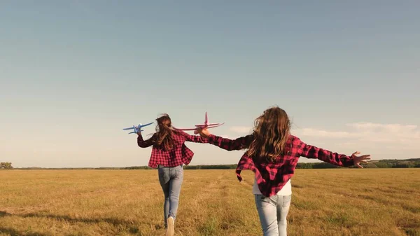 Crianças no fundo do sol com um avião na mão. Sonhos de voar. Feliz conceito de infância. Duas raparigas brincam com um avião de brincar ao pôr-do-sol. Silhueta de crianças brincando no avião — Fotografia de Stock