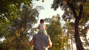 Babam parkta sevgili çocuğunun omuzlarını taşır. Baba, kızı ile birlikte ağaçların altında yürüyor. Ebeveynleri olan çocuk izin gününde yürür. Mutlu aile parkta dinleniyor..