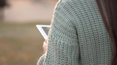 Şehrin kaldırımında yürüyen bir kadın tablet bilgisayarla çalışıyor. Yakın plan. Şehir caddesinde dijital tablet kullanan bir kız. Öğrenci kızların elleri tabletlere dokunuyor..