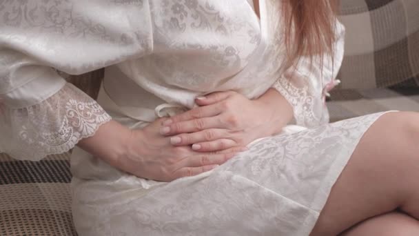 Młoda kobieta leżąca na kanapie przytulająca się do brzucha cierpiąca na ból brzucha. Chorą dziewczynę odczuwającą ból menstruacyjny, odpoczywającą na kanapie. Zapalenie błony śluzowej żołądka, ból miesiączki. Atak zapalenia wyrostka robaczkowego. Trzustka boli — Wideo stockowe