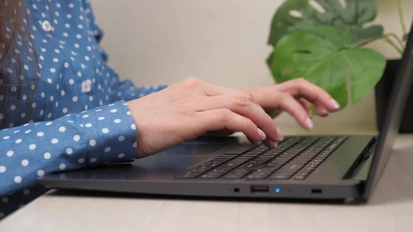 Les mains féminines d'une femme d'affaires travaillant sur ordinateur. Étudiante tapant du texte sur le clavier de l'ordinateur portable. Femme assise au bureau à la maison, travaillant en ligne. Une femme au bureau travaille sur un ordinateur moderne en ligne. — Photo