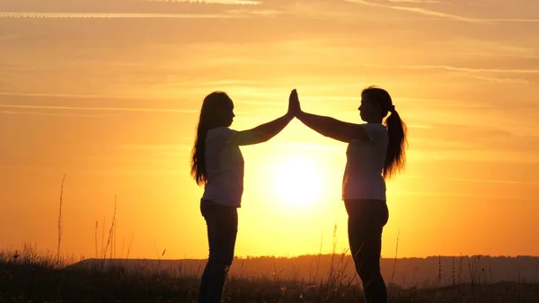 Bonne famille mère et fille dans le champ au soleil. Maman et fille se touchaient la paume des mains, se remettant un beau coucher de soleil. Concept de famille heureuse des enfants et de l'enfance. Maman et sa fille — Photo