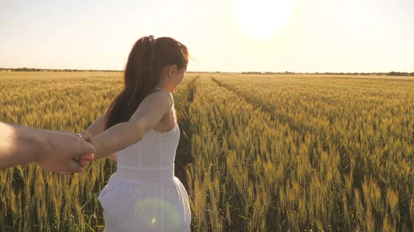 Beztroska kobieta i mężczyzna biegną przez pole pszenicy trzymając się za ręce w letnim słońcu. Rodzina farmerów. Dziewczyna i facet podróżują przez pole pszenicy. Darmowy romantyczny związek zakochanej pary — Zdjęcie stockowe