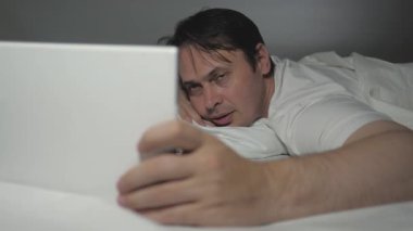 Evde bir erkek blogcu oturma odasındaki kanepede uzanıyor, tablet ve video iletişimi kullanıyor. Bir adam akşamları yatmadan önce internette dinleniyor. Postayı kontrol etmek, haberleri modern bir aletle okumak..