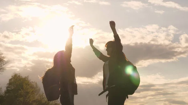 Viajantes livres do sexo feminino pulam e se alegram nos raios do sol. Turistas com mochilas, conheceram-se no topo da colina. Trabalho de equipa, caminhadas. Mova-se para vencer através de dificuldades. Vitória e a alegria do sucesso — Fotografia de Stock