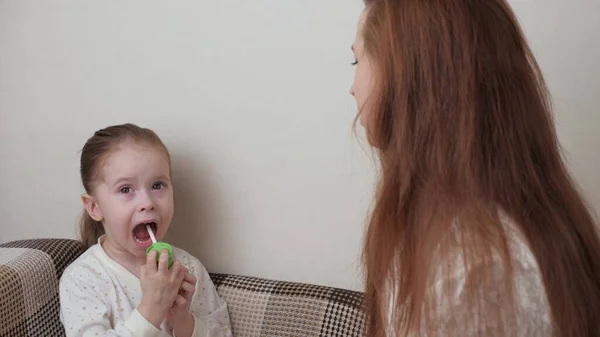 Anya úgy kezeli a babákat, hogy gyógyszert permetez a babák szájába. A gyerek játszik és orvosi ellátást nyújt a beteg anyjának. Anya influenzás gyerekről gondoskodik. Torokpermet — Stock Fotó