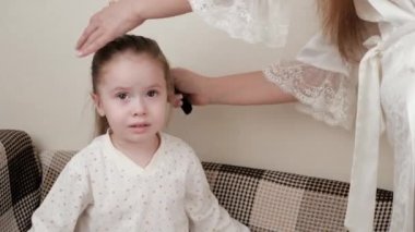 Annem yatmadan önce sevgili kızlarının saçlarını tarar. Pijamalı sağlıklı bir çocuk. Güzel bir kız için güzel bir saç stili. Mutlu bir aile. Annem küçük kızlarını örüyor..