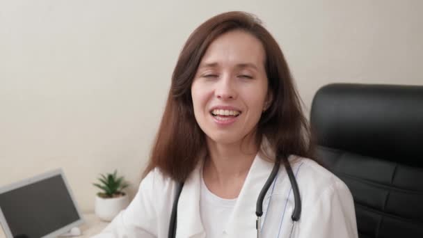 Læge Terapeut har en online samtale. Telemedicin. Smart kvindelig læge i hvid frakke og stetoskop ved hjælp af bærbar computer til at konsultere patienten eksternt på hospitalskontoret. Udnævnelse til familielæge – Stock-video