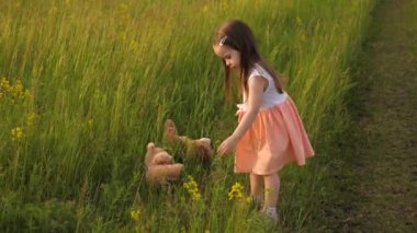 Parkta oyuncak ayıyla yemek yiyen mutlu bir bebek. Mutlu çocuk en sevdiği oyuncaklarla çimenlerde oynuyor. Küçük kız dışarıda oynuyor. Sağlıklı kız sahada oynuyor. Mutlu aile ve çocukluk.