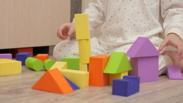 Kind speelt met gekleurde blokjes in kinderkamer op de vloer. Het kind bouwt een familiehuis. Educatieve spelletjes voor de ontwikkeling van kinderen. Een kind onderwijzen door te spelen. Gelukkige familie, dochter. — Stockvideo