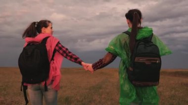 Renkli yağmurluk giyen mutlu kızlar sırt çantalarıyla seyahat ederler. Turist gezisindeki güzel kadınlar el ele gider. Takım çalışması. İnsanlar boş günlerinde doğada dinleniyorlar. Özgür bir adam. Temiz havada sağlıklı yürüyüşler.