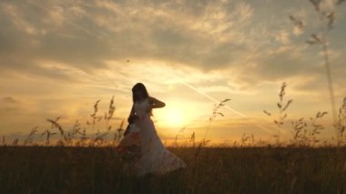 Mutlu bir aile ve çocukluk. Anne sevgili çocuğunun ellerinde uçarken sağlıklı bir bebek gibi gülüyor. Mutlu çocuk gün batımında annesiyle uçuyor. Anne ve bebek yaz parkında. Aile günü dışarıda.