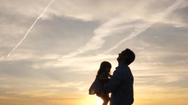 Baba ve küçük çocuk birlikte oynuyorlar, gülüyorlar ve sarılıyorlar. Babam mavi gökyüzüne mutlu bir kız çocuğu fırlatıyor. İyi yolculuklar. Bebeğin ebeveynin kollarında olması. Baba izinli. Mutlu aile kavramı.