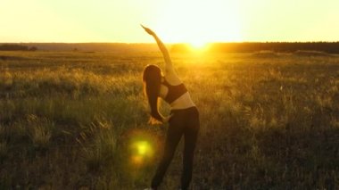 Sağlıklı, güzel bir kız şehrin dışında güneşlenir. Dışarıda antrenman ve ısınma egzersizleri. Özgür genç bir kadın gün batımında yaz parkında spor yapmaya gider. Kız sahada temiz hava soluyor..