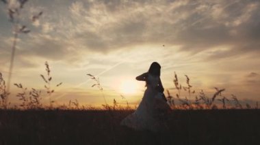 Anne sevgili çocuğunun kollarında dönüyor, kızı gülüyor, sağlıklı çocuk uçuyor. Mutlu bir aile ve çocukluk. Çocuk oynar, gün batımında annesiyle uçar. Anne ve bebek yaz parkında..