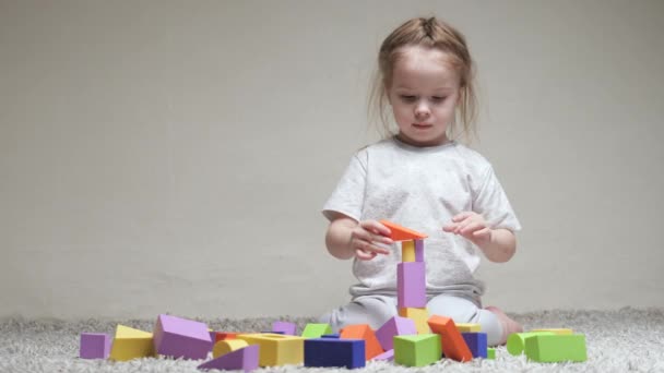 Ten kluk staví rodinný dům. Vzdělávací hry pro rozvoj dětí. Učit dítě hrát si. Šťastná rodina. Dcera si hraje s barevnými kostkami v dětském pokoji na podlaze.
