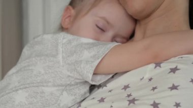 Sevgi dolu genç bir anne kucaklar ve kollarında uyuyan tatlı kızını sakinleştirir. Kibar, şefkatli bir anne ve yatak odasında kucaklaşan sevimli küçük bir kız bebek. Anne ve bebek hassas anlardır..