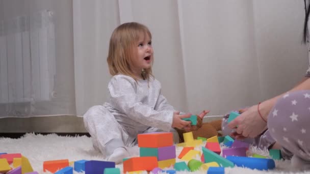 Mam en dochter spelen kleurrijke kubussen in de kinderkamer. Gelukkige familie. Educatieve spelletjes voor de ontwikkeling van kinderen. Het onderwijzen van het kind door middel van speelactiviteiten. Mam en dochter bouwen ouderlijk huis. — Stockvideo