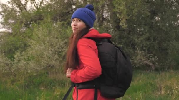 Free woman traveler walks with a backpack along the forest road, happy girl smiles. Hiking and outdoor adventure. Freedom and healthy lifestyle. Healthy carefree girl traveling. Travel and adventure. — Stock Video