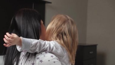 Mutlu aile, anne ve bebek evde sarılıp yatıyorlar. Sevimli küçük kız annesine sarılıyor. Çocuğun sevimli küçük kızı, akşam yatmadan önce annesine sarılıyor. Aile kucaklaşması