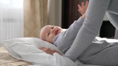 Bebek ve genç anne sabahları yatakta oynarlar. Küçük oğlan, annesinden olan kızı. Mutlu bir anne ve yatak odasında kucaklaşan sevimli küçük bir kız bebek. Anne ve bebek hassas anlardır. Mutlu baba ailesi